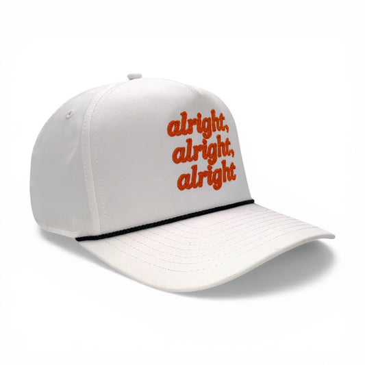 Angled side view of white hat with orange “alright, alright, alright” embroidery and black rope