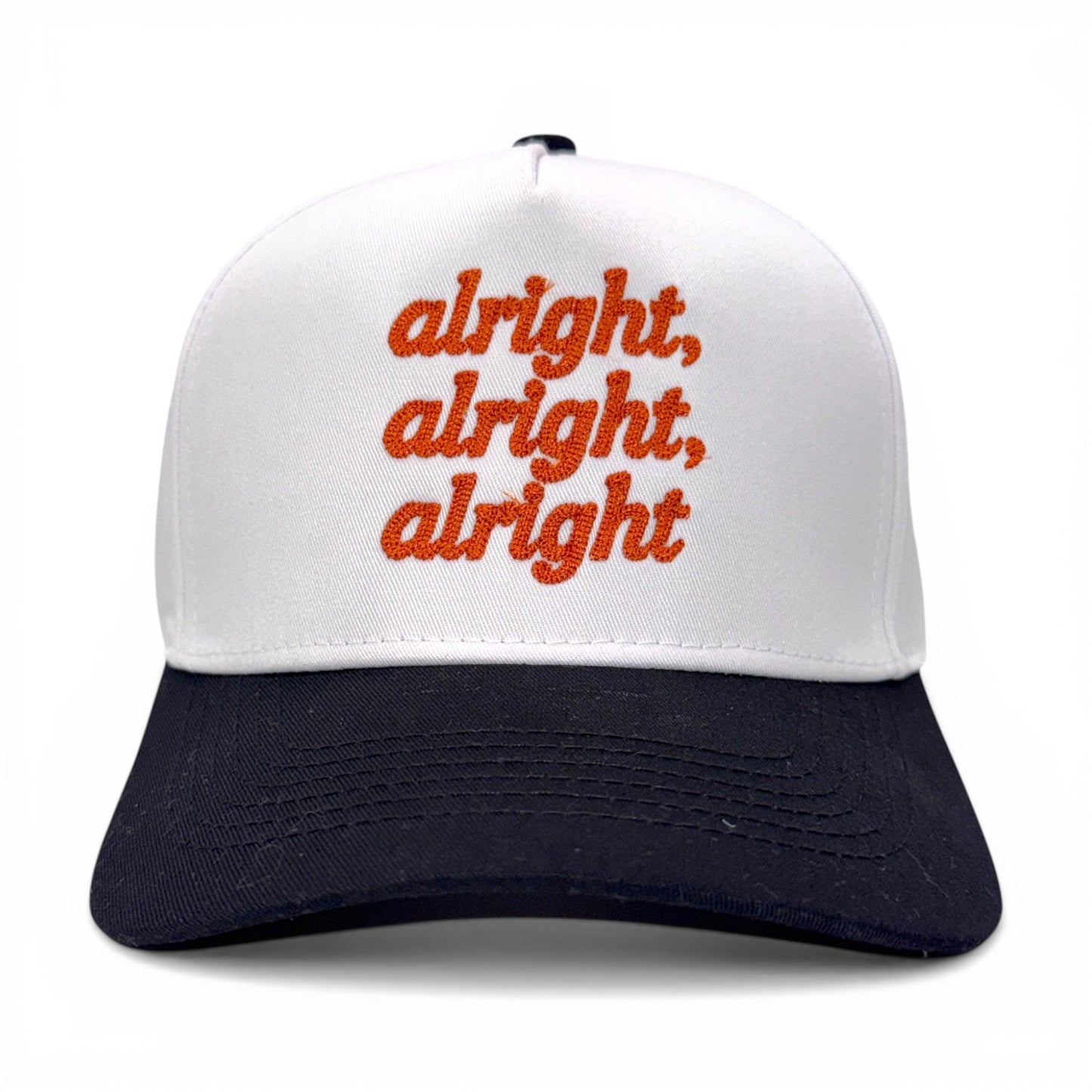 Front view of white and black bill hat with orange “alright, alright, alright” embroidery
