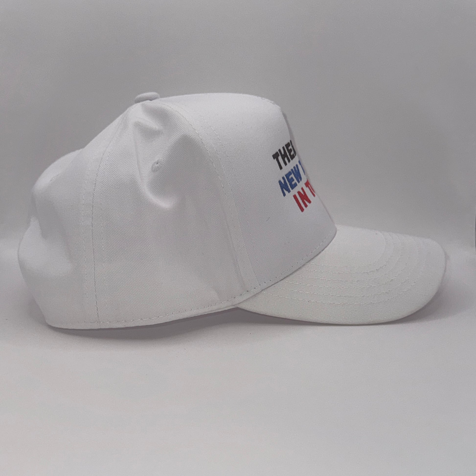 “White snapback hat with embroidered text ‘There’s a new tariff in town’ in black, blue, and red”