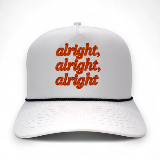 Front view of white rope hat with orange “alright, alright, alright” embroidery and black rope