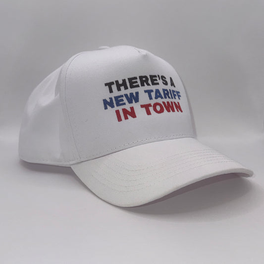 “White snapback hat with embroidered text ‘There’s a new tariff in town’ in black, blue, and red”