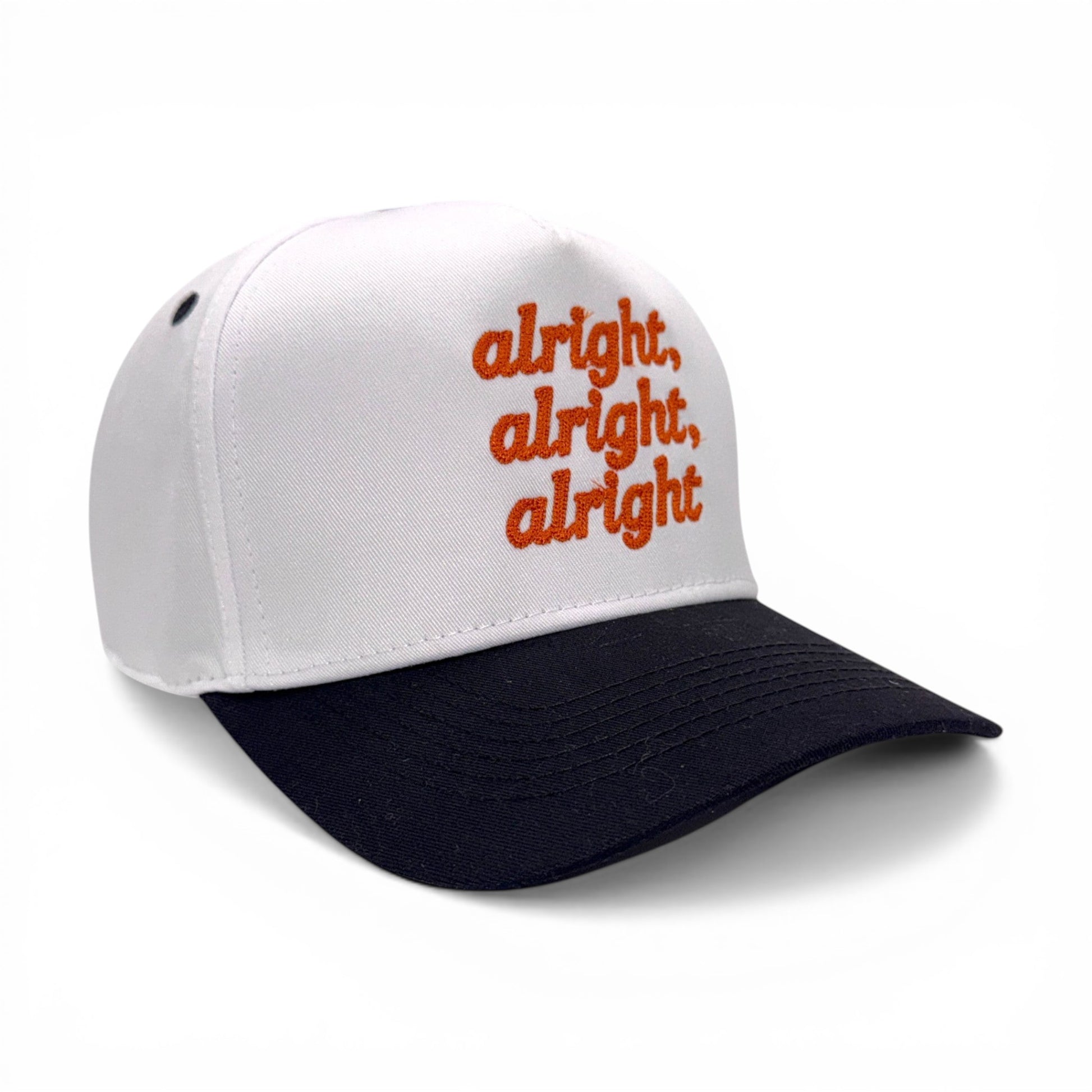 Angled side view of white hat with black bill and orange embroidered text
