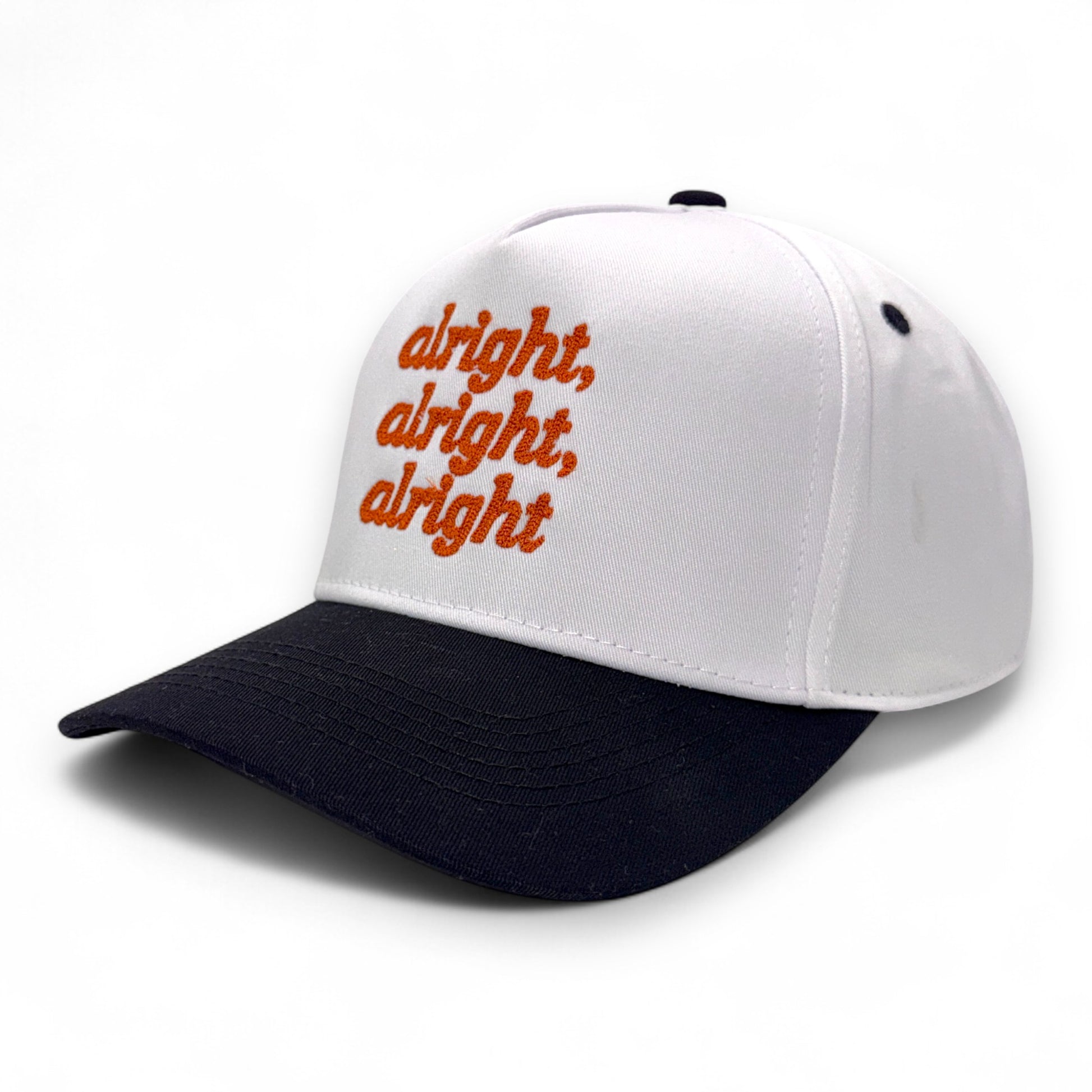 Angled side view of white hat with black bill and orange embroidered text
